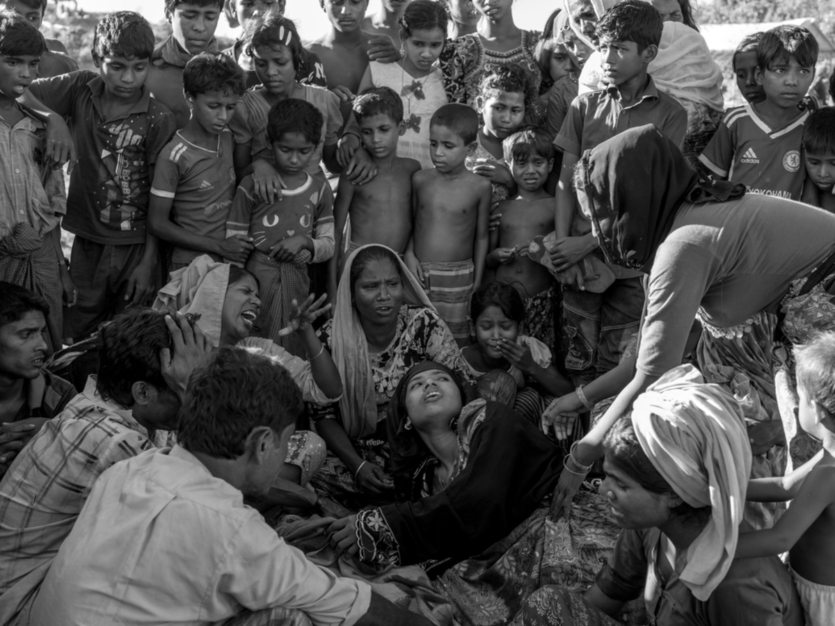 Relatives of Amina Khatun, a 60-year-old Rohingya refugee who died from complications related to starvation, mourn next to her body before her burial in the Balukhali refugee camp.