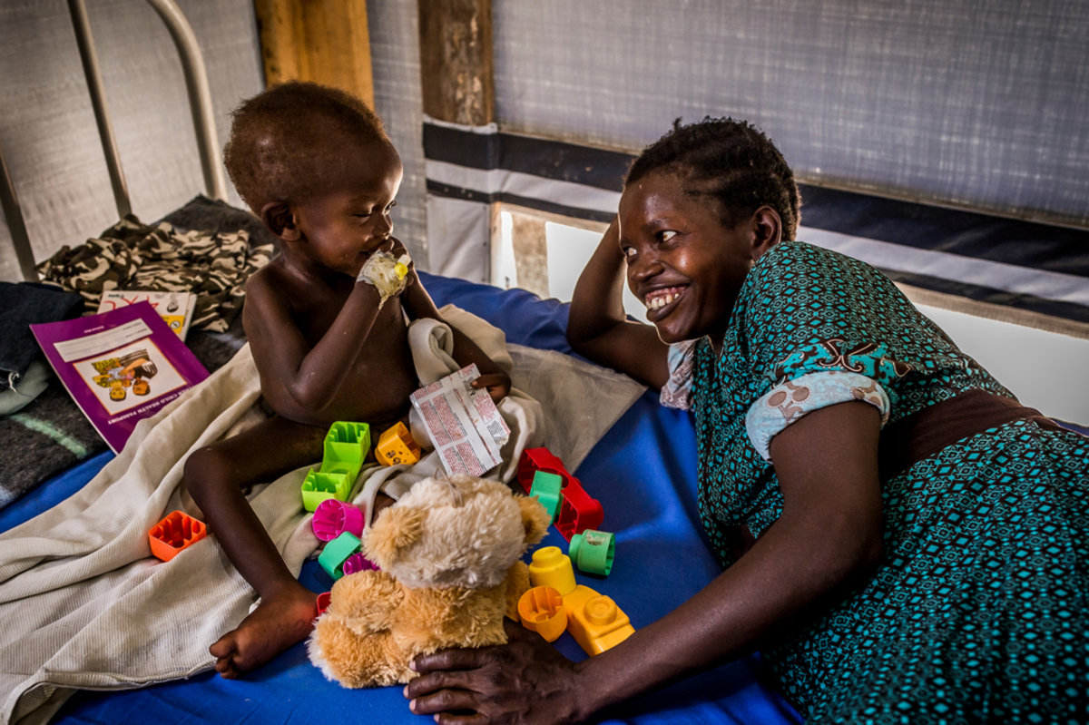 In Patient Department of Bidibidi, MSF Health Center. A young boy suffering from malnutrition with his mother. In Patient Department of Bidibidi, MSF Centre de Santé. Un jeune garçon souffrant de malnutrition avec sa mère.